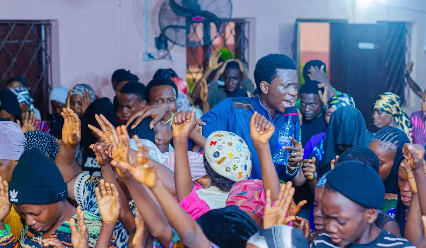 Worshippers with raised hands praying together at a service in Aiyepe, Ijebu